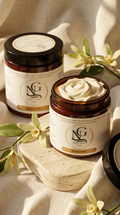 Two jars of NG cream on a textured surface with vanilla flowers.