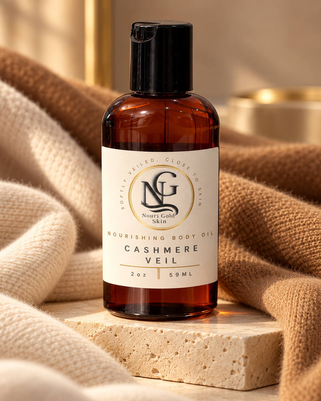 An amber plastic bottle of Nightlight Skincare Cashmere Veil nourishing body oil with a black cap and cream label, styled on a stone block with beige knit fabric.